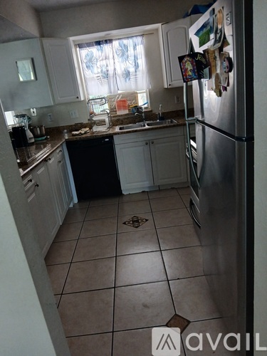 A kitchen with a refrigerator, sink, and cabinets.
