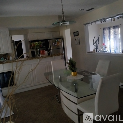 A modern kitchen with a glass table and white chairs.