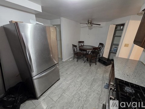 A kitchen with a refrigerator, table and chairs.