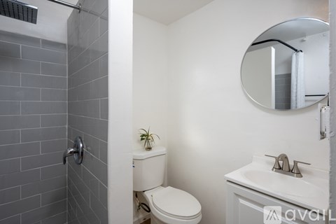 A bathroom with a toilet, sink, and mirror.