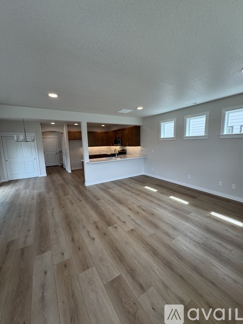 A spacious room with wooden flooring and white walls.