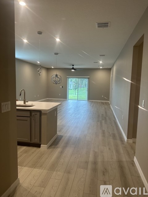 A modern kitchen with wooden floors and a large window.