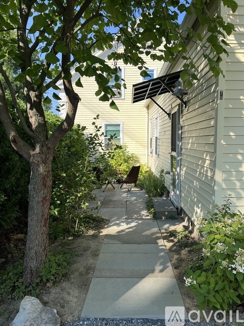 A tree in a yard with a house in the background.