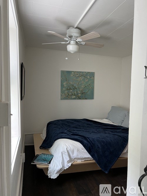 A bedroom with a bed and a ceiling fan.