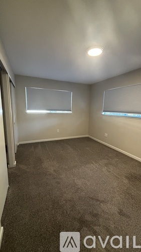 A room with a carpeted floor and a window with blinds.