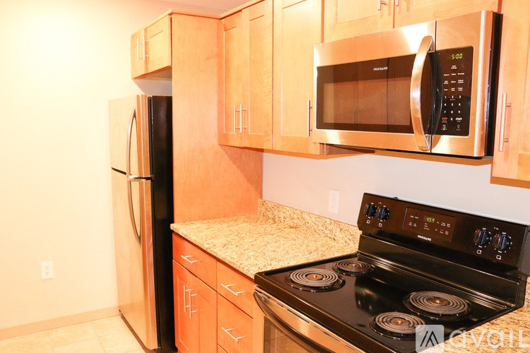 A kitchen with a stove, microwave, and refrigerator.