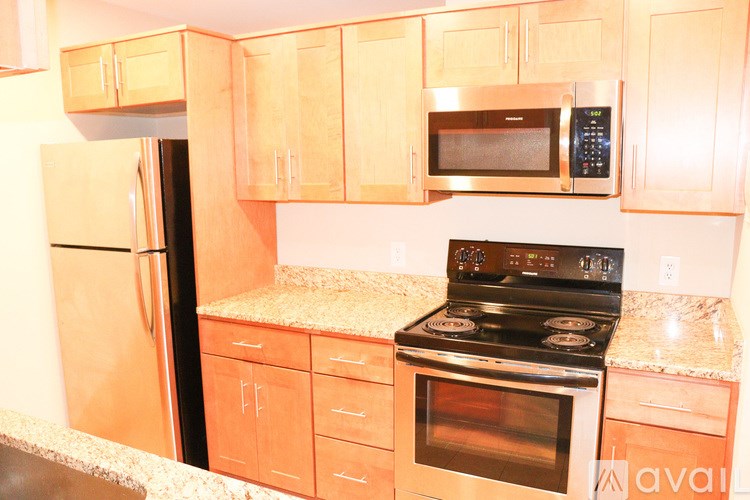 A kitchen with a stove, refrigerator, and microwave.