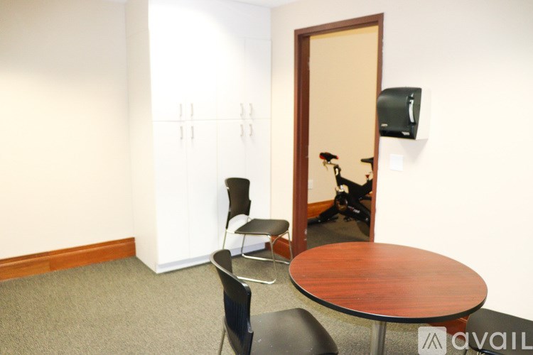 A room with a table and chairs and a television on the wall.