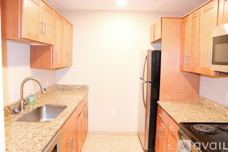 A kitchen with wooden cabinets and a black refrigerator.