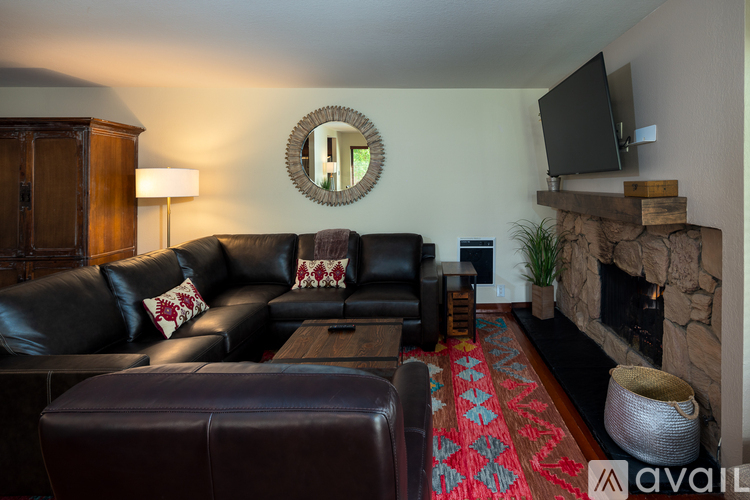 A living room with a black leather couch and a wooden cabinet.