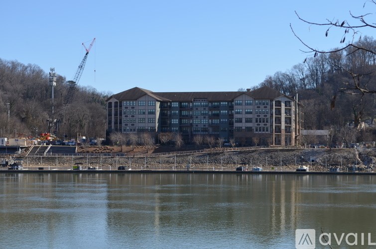 A large building with a crane in the background is situated by a body of water.