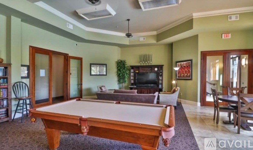 A pool table is in the middle of a room with a green wall.