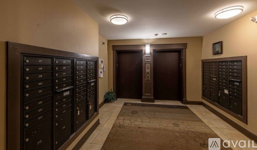 A hallway with a row of mailboxes on the left and right, leading to a central door.