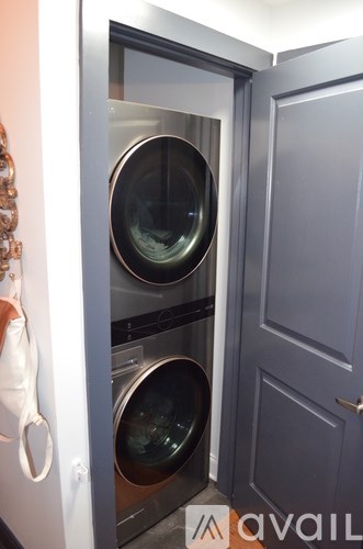 A washing machine is in a small space between a door and a wall.