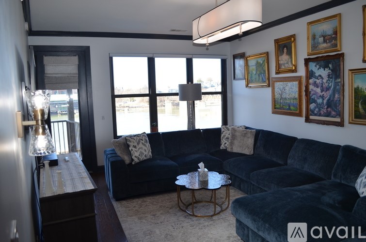 A living room with a dark blue couch, a coffee table, and a wall with framed pictures.