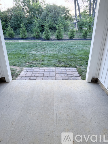 A patio with a brick border leads to a grassy area.