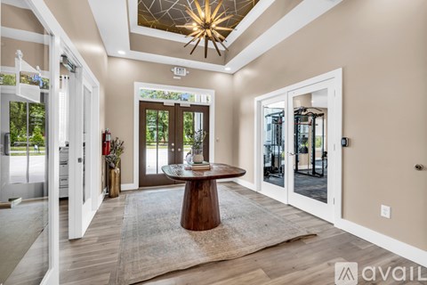 A modern living room with a round wooden table and a chandelier hanging from the ceiling.