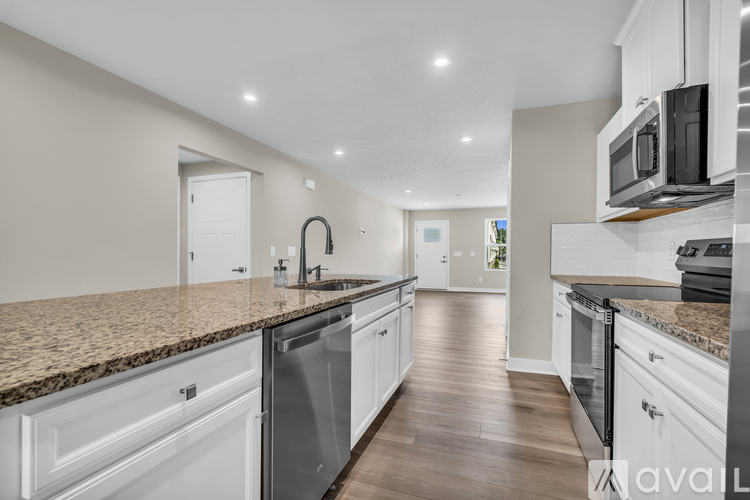 A modern kitchen with white cabinets and a granite countertop.