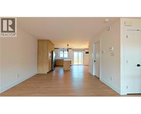 A spacious living room with wooden floors and white walls.