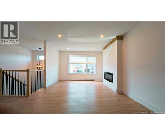 A spacious living room with a staircase on the left and a large window on the right.