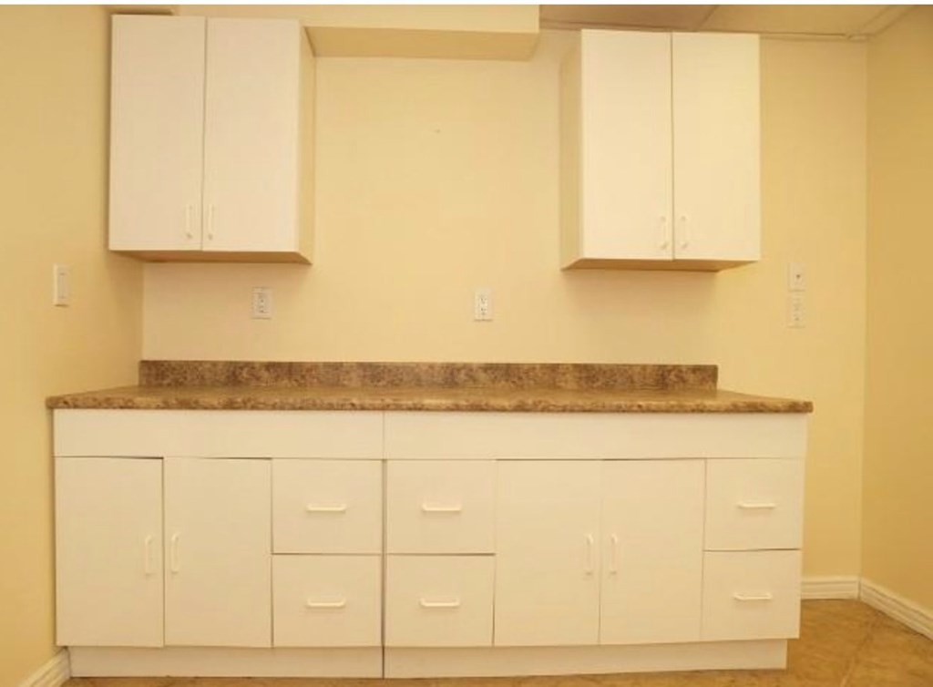 A kitchen with white cabinets and a granite countertop.