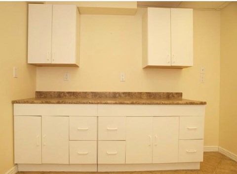 A kitchen with white cabinets and a granite countertop.