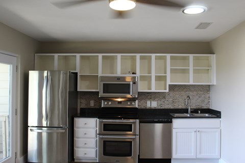A modern kitchen with a stainless steel refrigerator and white cabinets.
