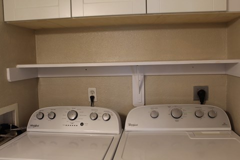 Two white Washing machines in a laundry room.