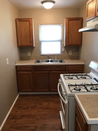 A kitchen with a white stove top oven and wooden cabinets.
