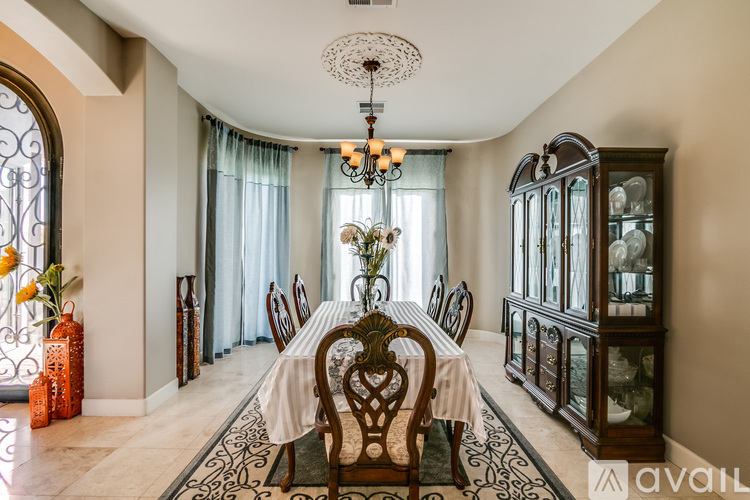A dining room with a table set for six and a chandelier hanging from the ceiling.