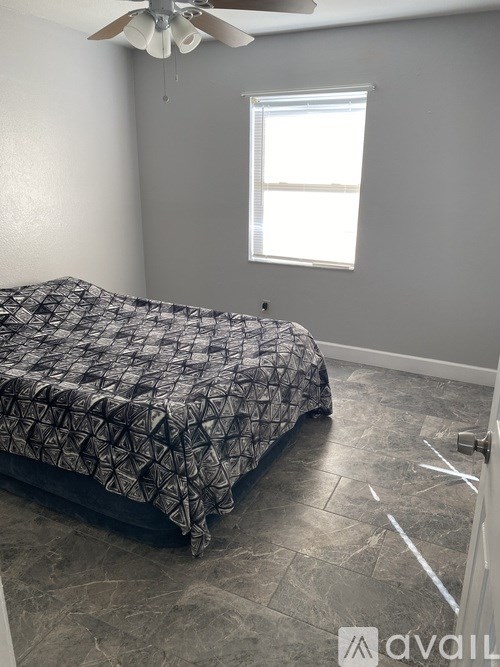 A bedroom with a bed, ceiling fan, and a window.
