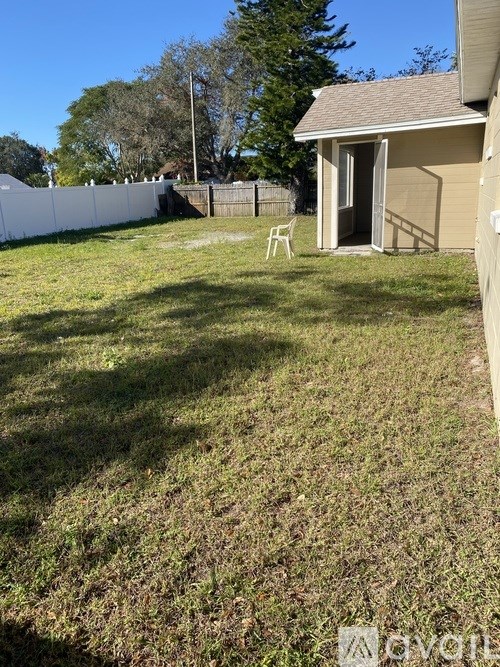 A backyard with a white fence and a small house.