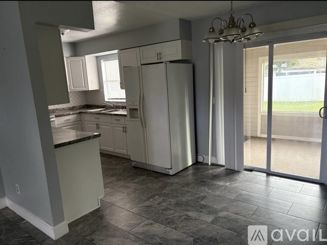 A kitchen with a refrigerator, cabinets, and a countertop.