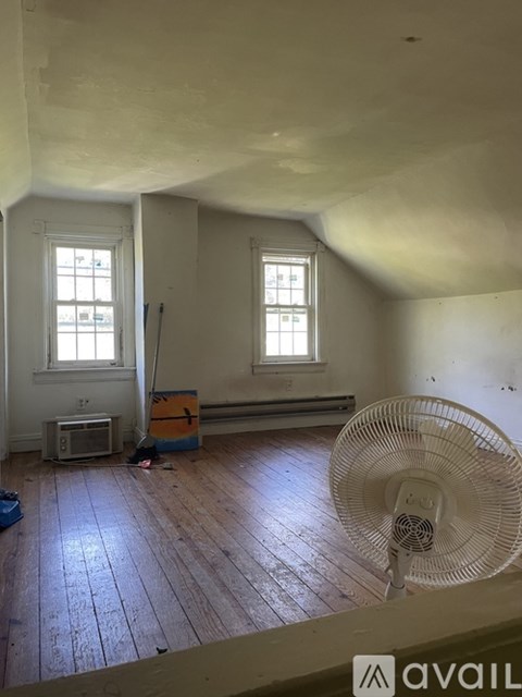 A room with wooden floors and two windows.