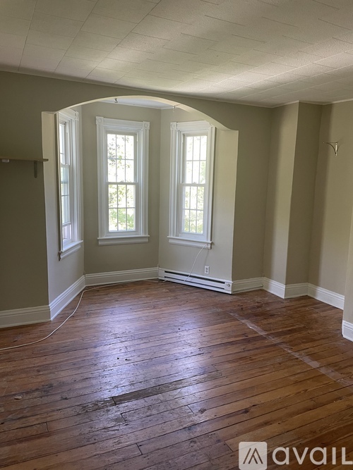 A room with wooden floors and two windows.