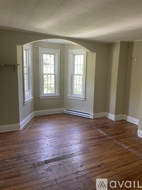 A room with wooden floors and two windows.