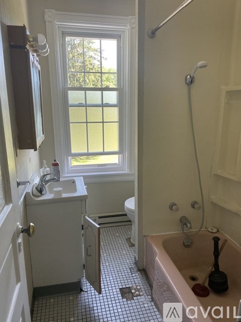 A bathroom with a tub, sink, and window.