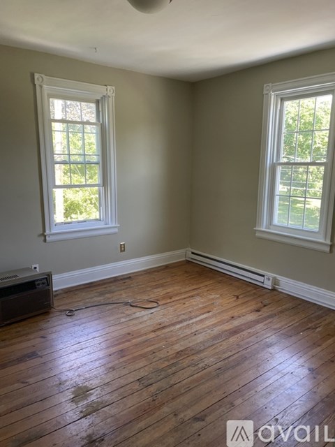 A room with wooden floors and two windows.