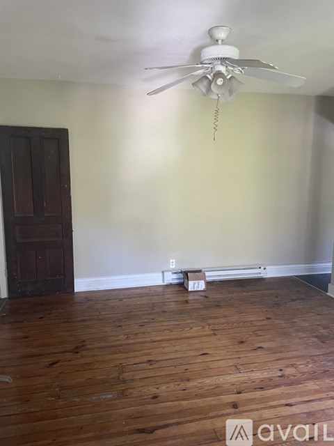 A room with a ceiling fan and wooden floors.