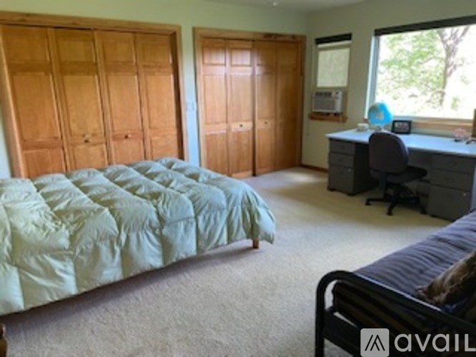 A bedroom with a bed, desk, and two closets.