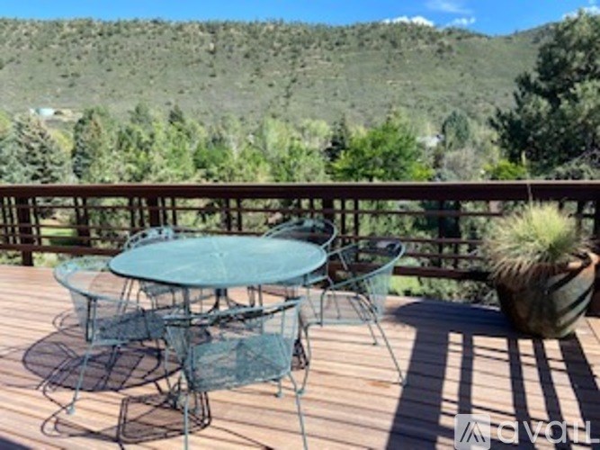A table and chairs set on a deck with a mountain in the background.