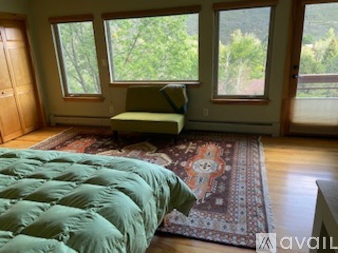 A room with a green comforter on the bed.