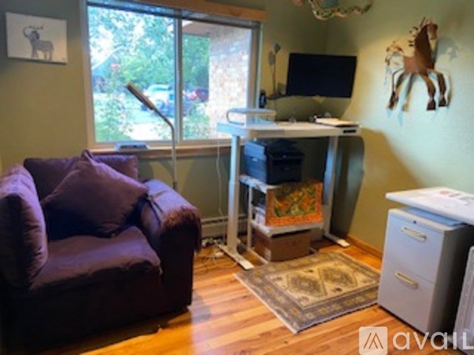 A room with a purple couch, a desk, and a printer.