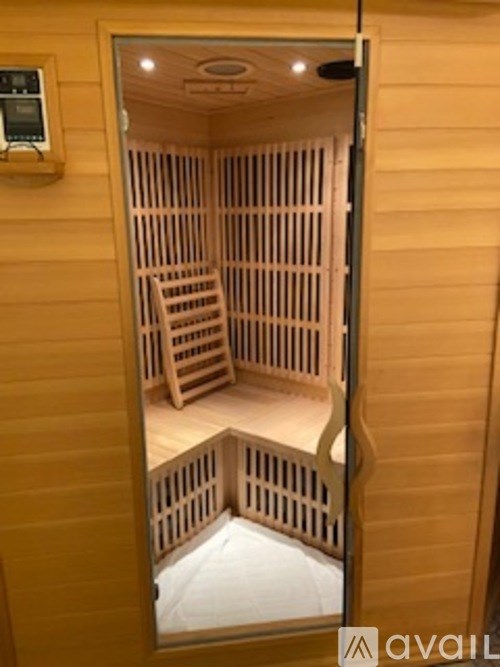 A wooden sauna with a glass door and a control panel on the wall.