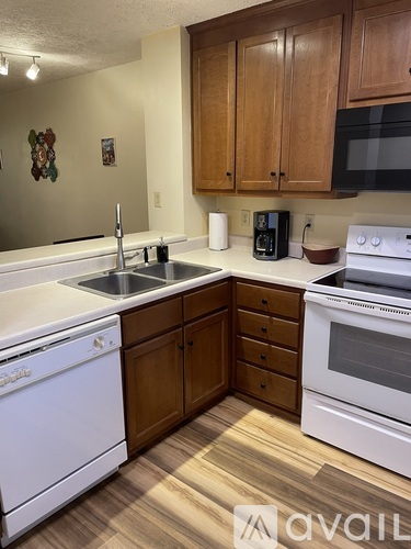 A kitchen with white appliances and wooden cabinets.