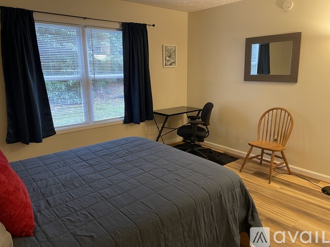 A bedroom with a bed, chair, and window.