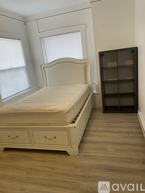 A bedroom with a large bed and a wooden bookshelf.