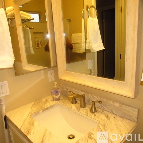 A bathroom with a marble counter top and a large mirror.
