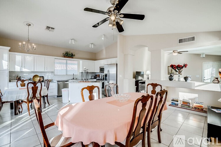 A dining room with a table set for six with a pink tablecloth.