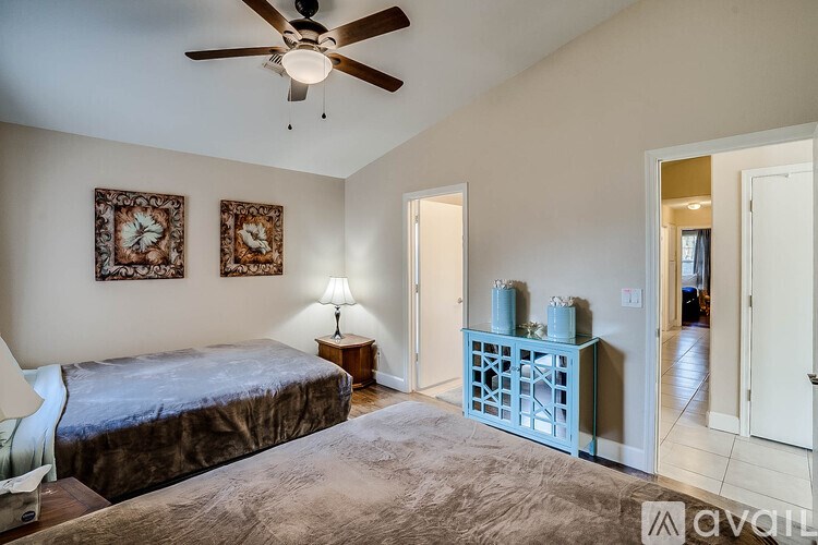A bedroom with a bed, a ceiling fan, and two wall clocks.